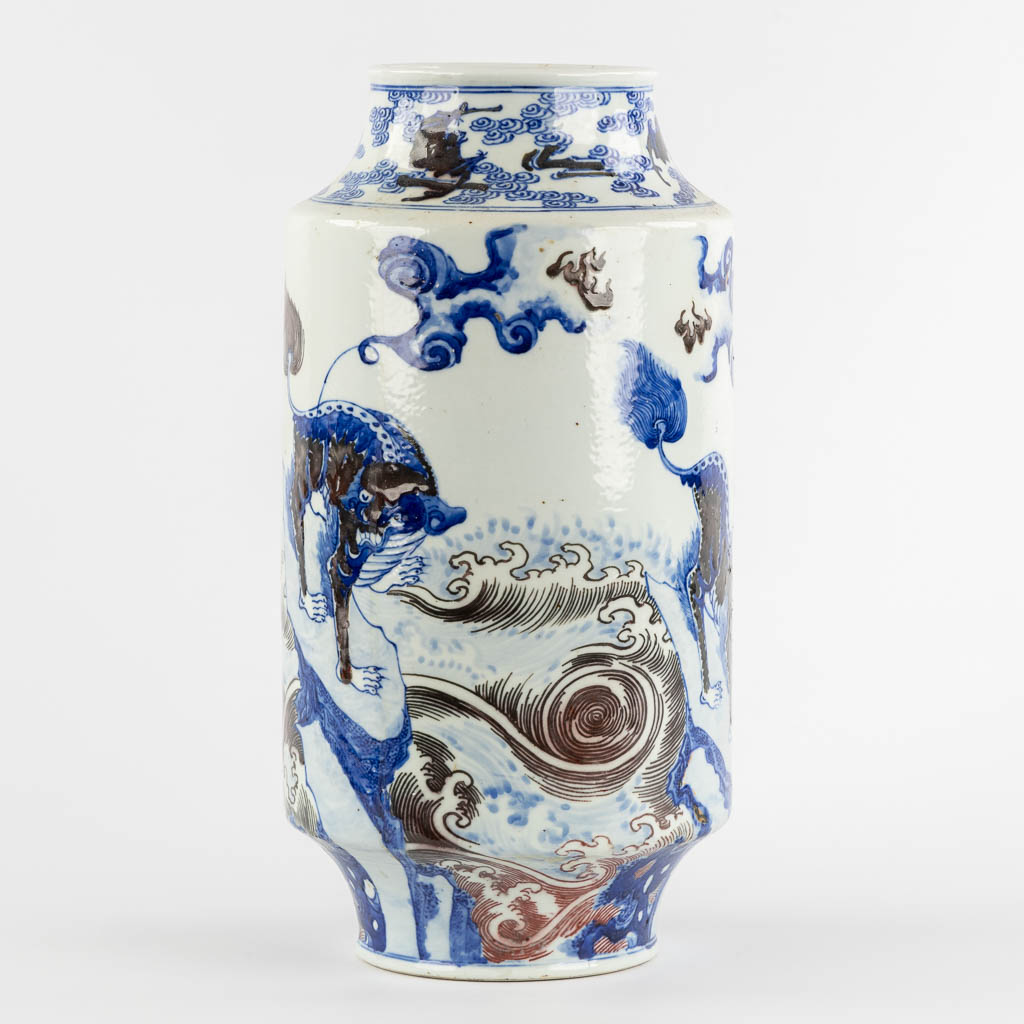 A Chinese Rouleau vase with a blue, black and white Foo Dog. Kangxi mark, 19th C. (H:39 x D:29 cm)