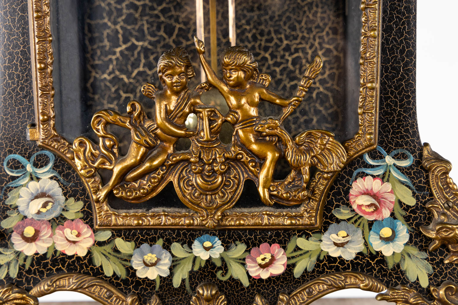 A cartel clock on a base, floral decor and mounted with putti. 20th C. (L:25 x W:44 x H:193 cm)