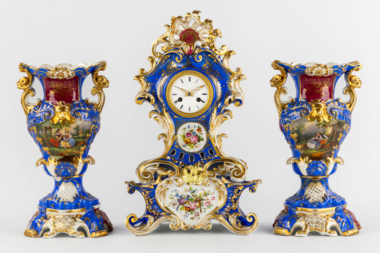 A Vieux Paris mantle clock with two side pieces, in the style of Jacob Petit. 19th C. (L:13 x W:25 x H:41 cm)