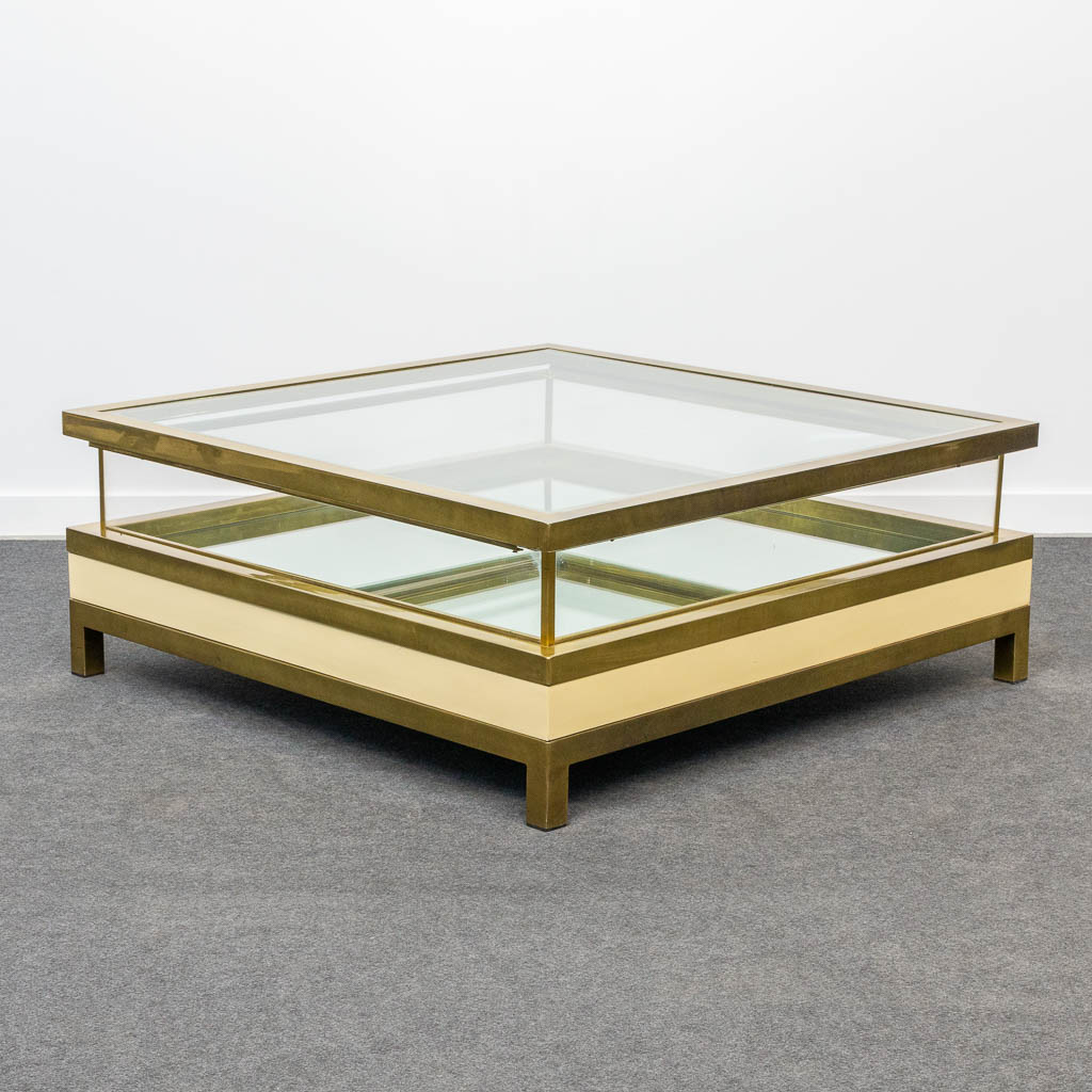 A mid-century coffee table made by Maison Jansen with a slide glass top. Made of glass and brass. 