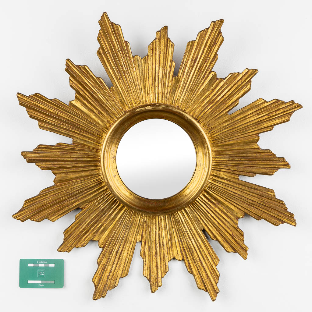 A wood-sculptured sunburst mirror with bent rays, convex glass.