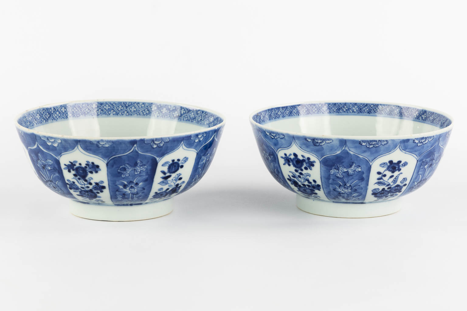 A pair of Chinese bowls, blue-white with a floral and pomegranate decor. 19th C. (H:8,5 x D:18 cm)