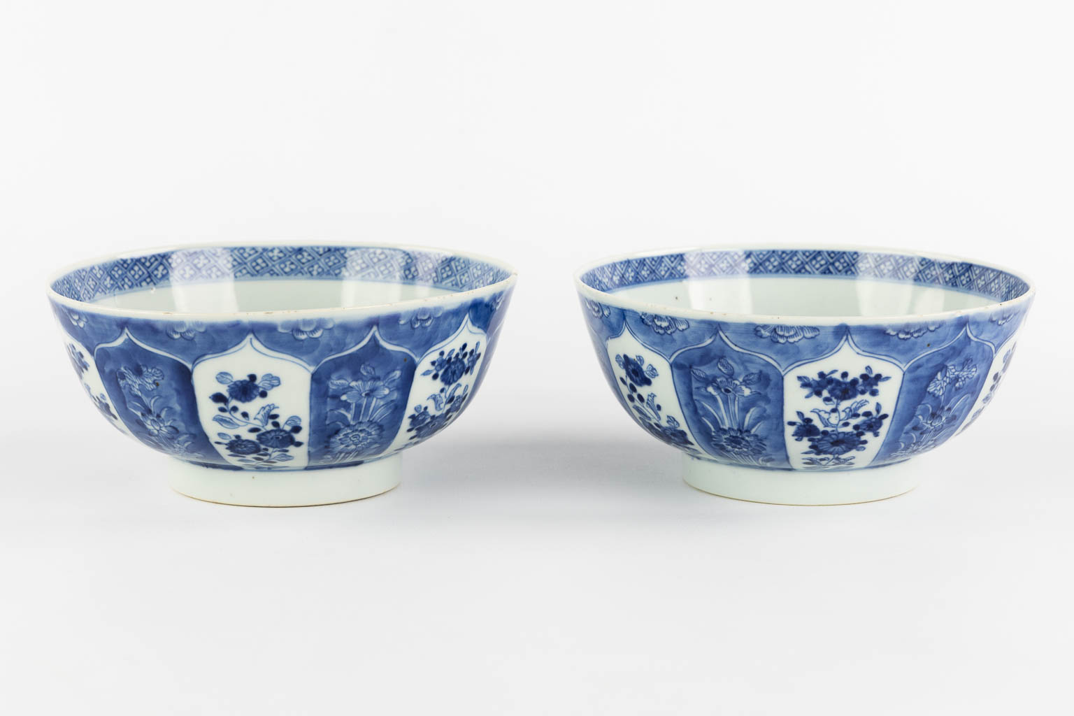 A pair of Chinese bowls, blue-white with a floral and pomegranate decor. 19th C. (H:8,5 x D:18 cm)