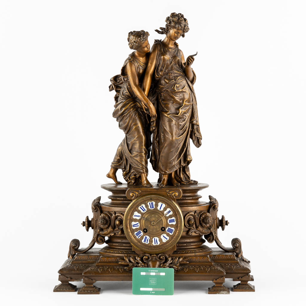 A large mantle clock with two ladies, patinated spelter. Circa 1900. (L:18 x W:42 x H:58 cm)