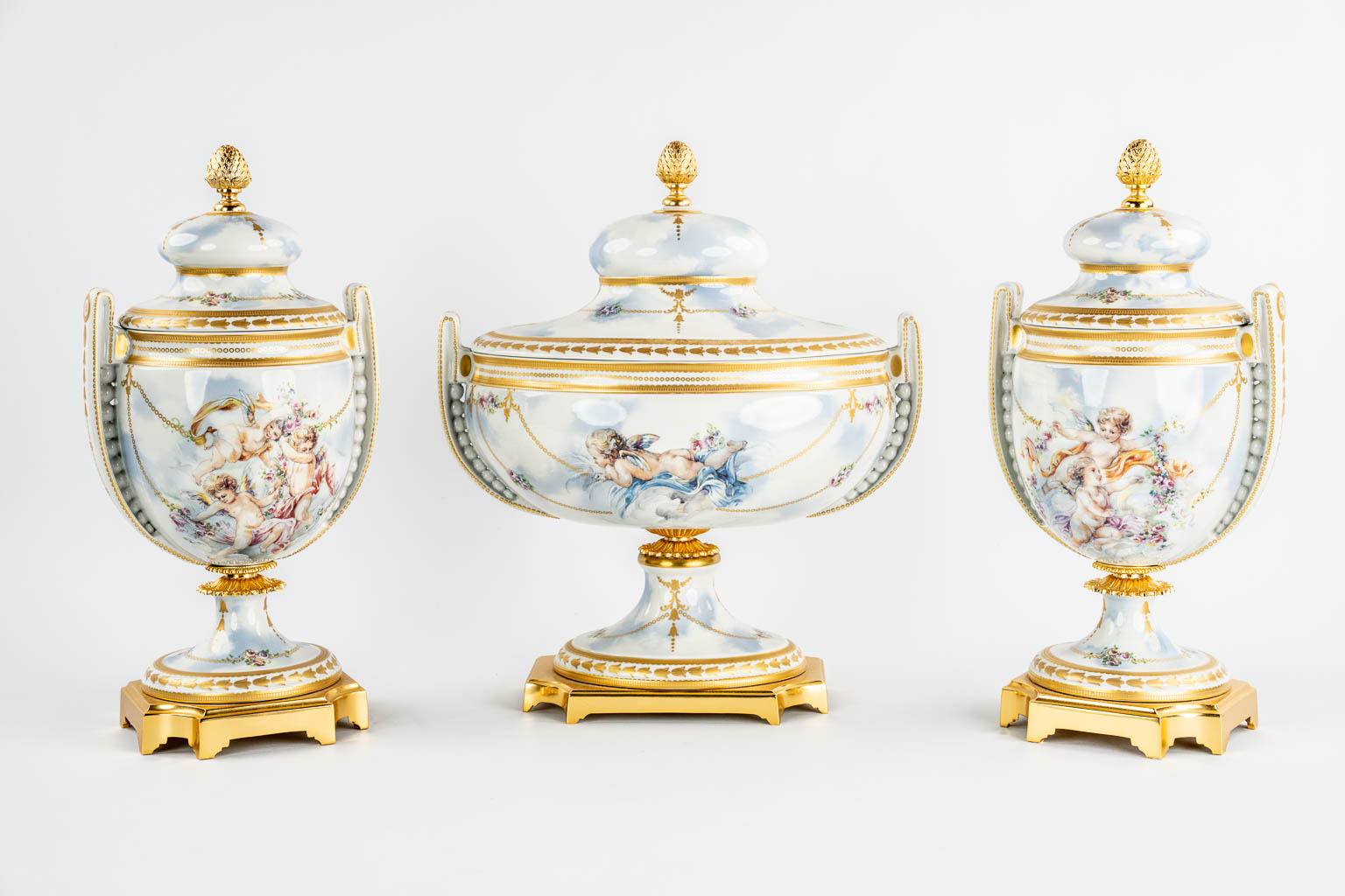 A three piece mantle garniture, porcelain vases with a lid, decorated with Angels. Italy, 20th C.