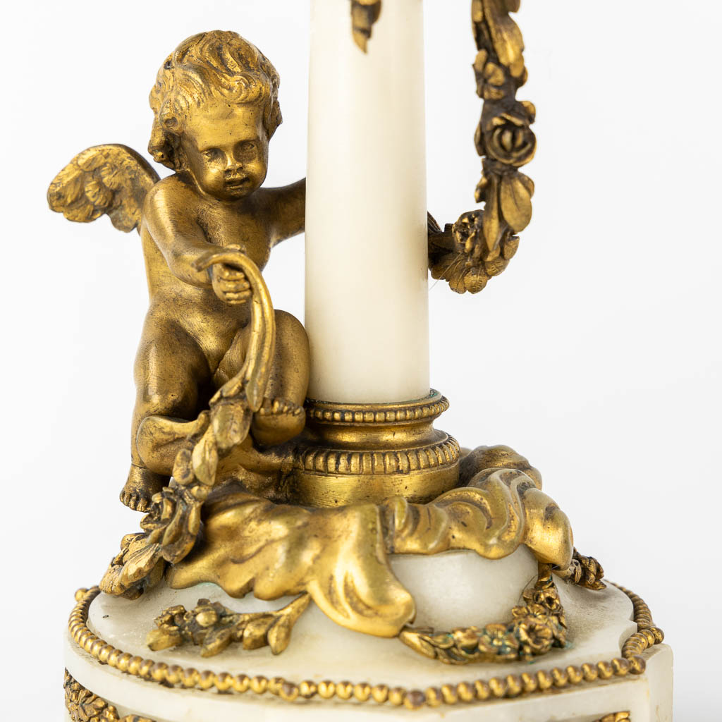 A three-piece mantle garniture clock and candelabra, bronze and marble, 19th C. (L:11 x W:27 x H:36 cm)