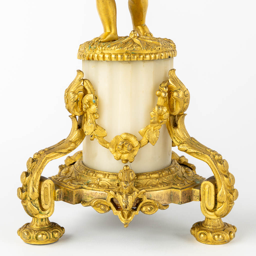 A three-piece mantle garniture clock, Cupid. Gilt bronze and Carrara marble. (L:13 x W:17 x H:37 cm)