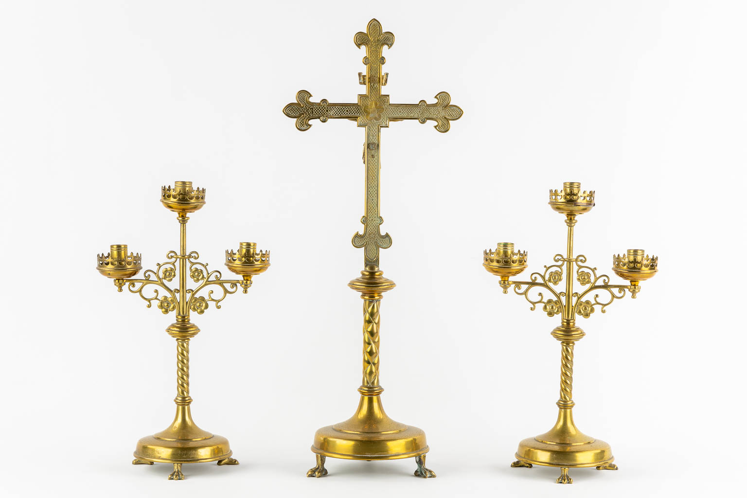 An altar crucifix with two matching candelabra, brass in a Gothic Revival style. (W:23 x H:58 cm)