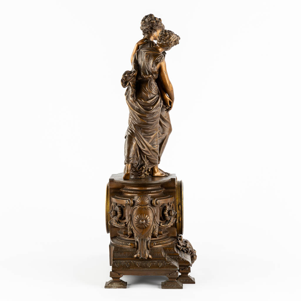 A large mantle clock with two ladies, patinated spelter. Circa 1900. (L:18 x W:42 x H:58 cm)