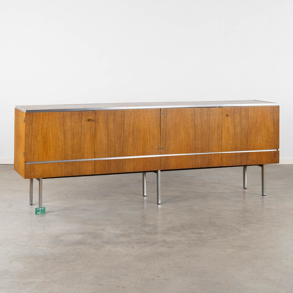 Een mid-century dressoir, houtfineer en gechromeerd metaal. Roger De Winter. (L:46 x W:237 x H:84 cm)