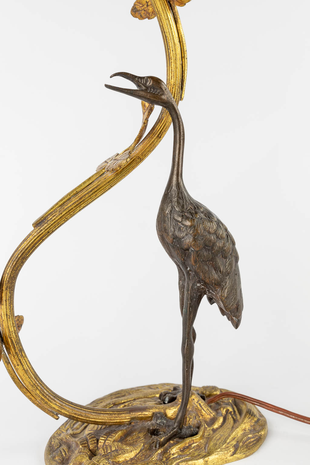 Een tafellamp met grote vogel, waarschijnlijk een reiger. Gepatineerd en verguld brons, circa 1900. (W:33 x H:37 cm)