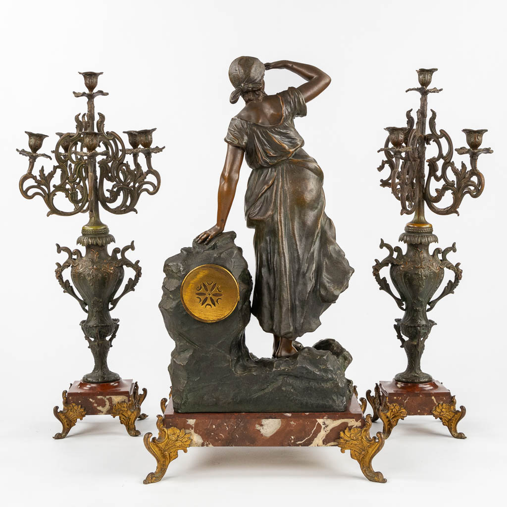 A three-piece mantle garniture clock and candelabra, spelter mounted on marble. Circa 1900. (L:28 x W:42 x H:77 cm)