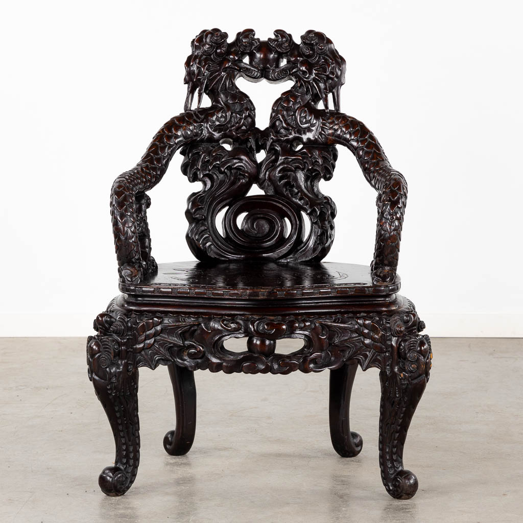 A Chinese sculptured hardwood armchair with a dragon decor. 