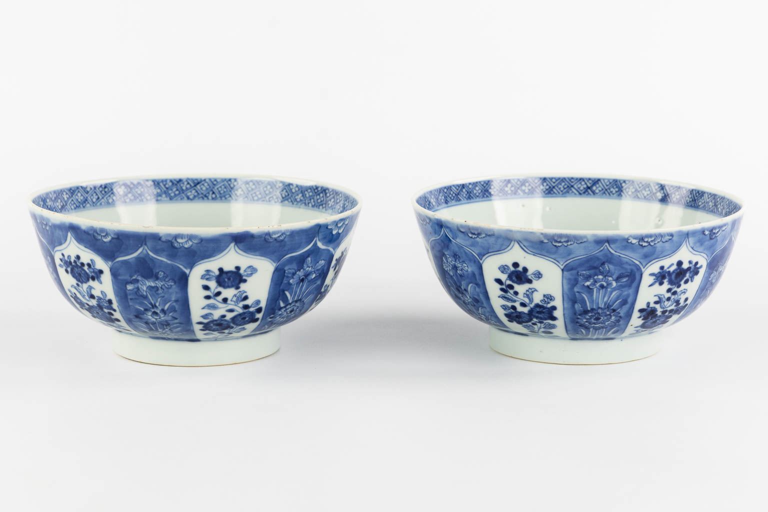 A pair of Chinese bowls, blue-white with a floral and pomegranate decor. 19th C. (H:8,5 x D:18 cm)