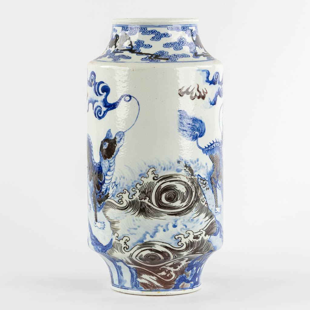 A Chinese Rouleau vase with a blue, black and white Foo Dog. Kangxi mark, 19th C. (H:39 x D:29 cm)