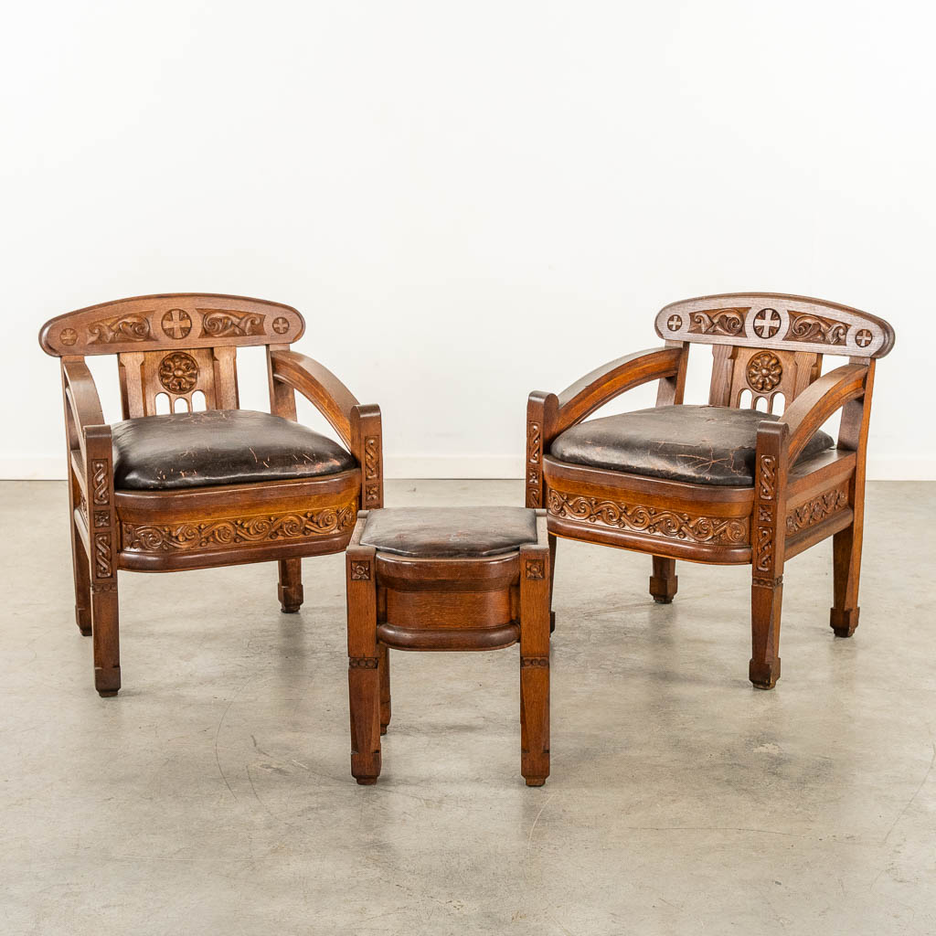 A pair of sculptured wood armchairs and footstool, used in an Art Deco chapel, leather seat. (L:60 x W:60 x H:73 cm)