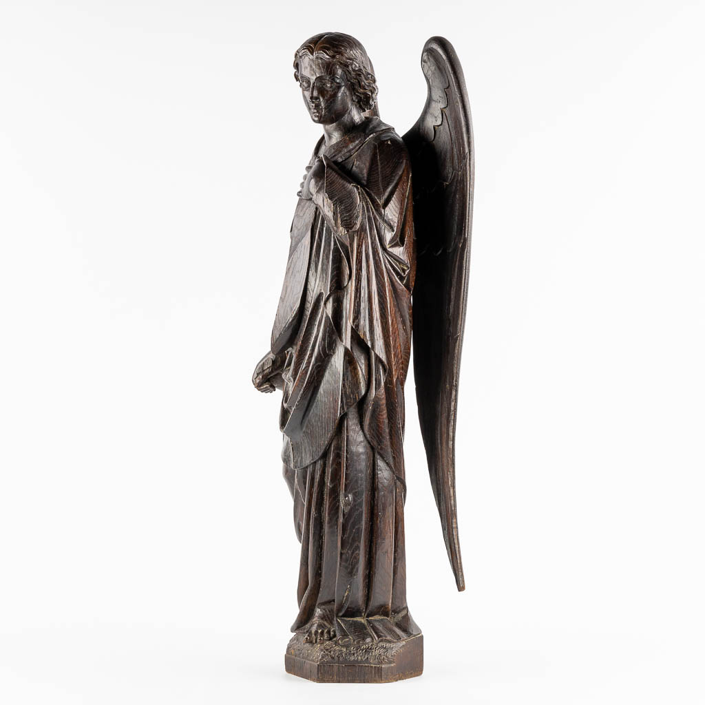 A large wood sculptured figurine of an angel, oak, 19th C. (L:20 x W:40 x H:95 cm)