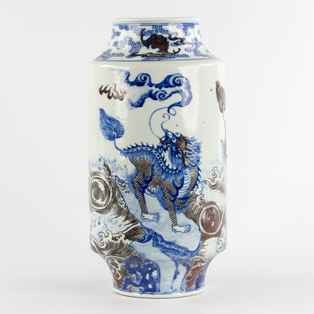 A Chinese Rouleau vase with a blue, black and white Foo Dog. Kangxi mark, 19th C. (H:39 x D:29 cm)