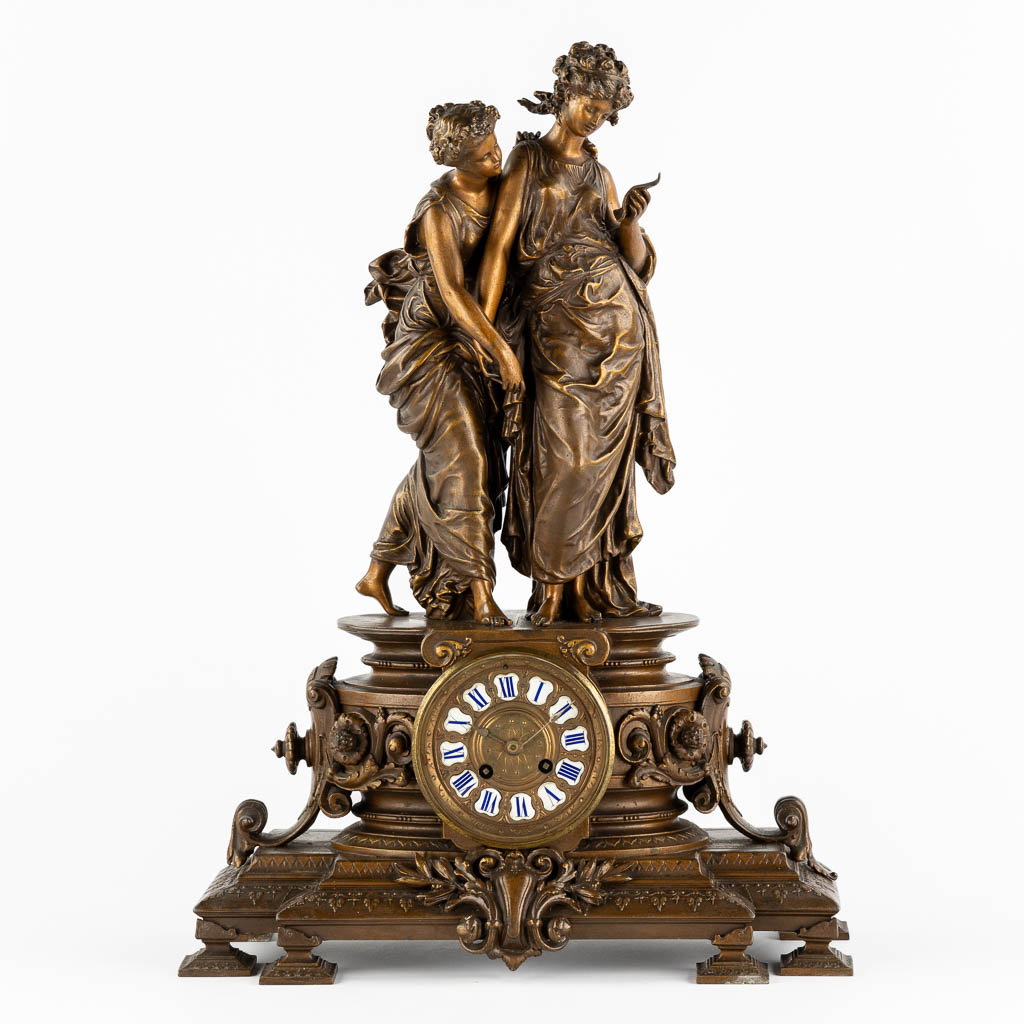 A large mantle clock with two ladies, patinated spelter. Circa 1900. (L:18 x W:42 x H:58 cm)