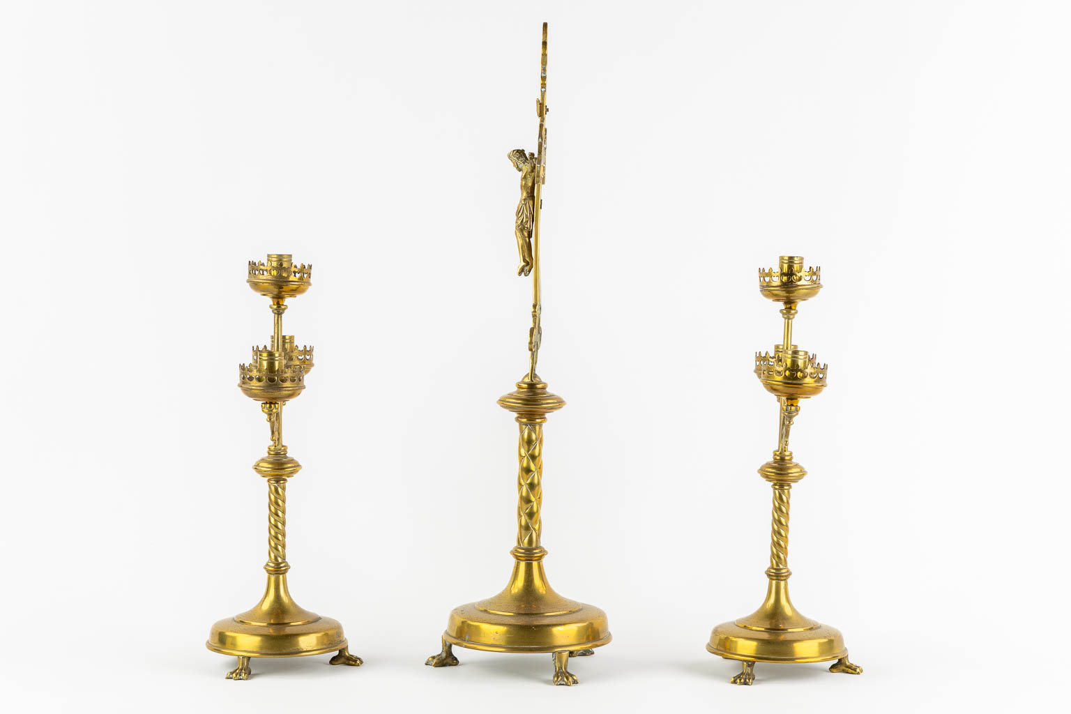 An altar crucifix with two matching candelabra, brass in a Gothic Revival style. (W:23 x H:58 cm)