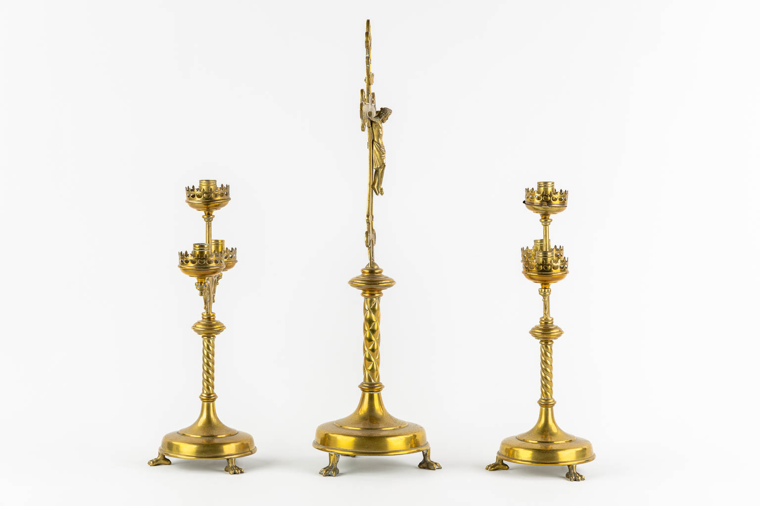 An altar crucifix with two matching candelabra, brass in a Gothic Revival style. (W:23 x H:58 cm)