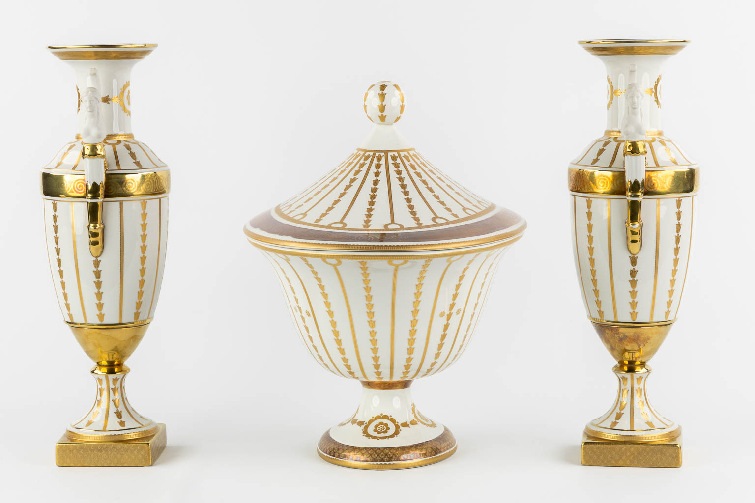 Mangani, Italy, a three-piece garniture, gilt porcelain in Empire style. (L:32 x W:43 x H:40 cm)