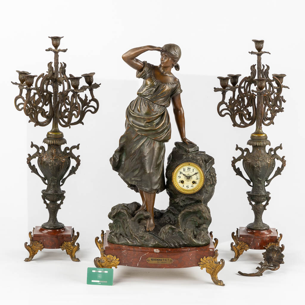 A three-piece mantle garniture clock and candelabra, spelter mounted on marble. Circa 1900. (L:28 x W:42 x H:77 cm)