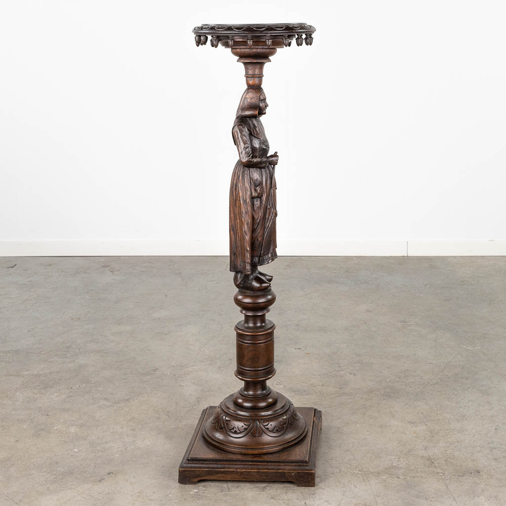 A pedestal with a wood sculptured figurine in Breton style. Circa 1900. (L: 31,5 x W: 31,5 x H: 107 cm)