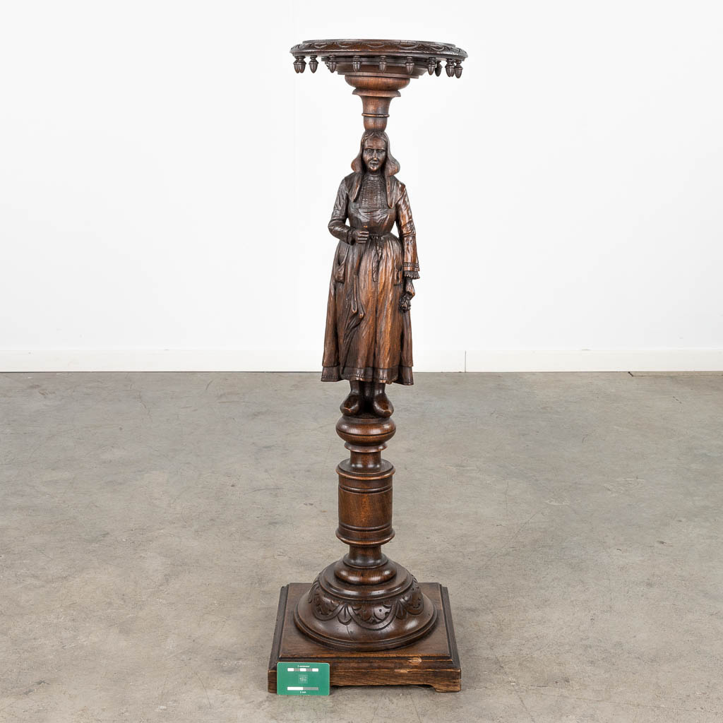 A pedestal with a wood sculptured figurine in Breton style. Circa 1900. (L: 31,5 x W: 31,5 x H: 107 cm)