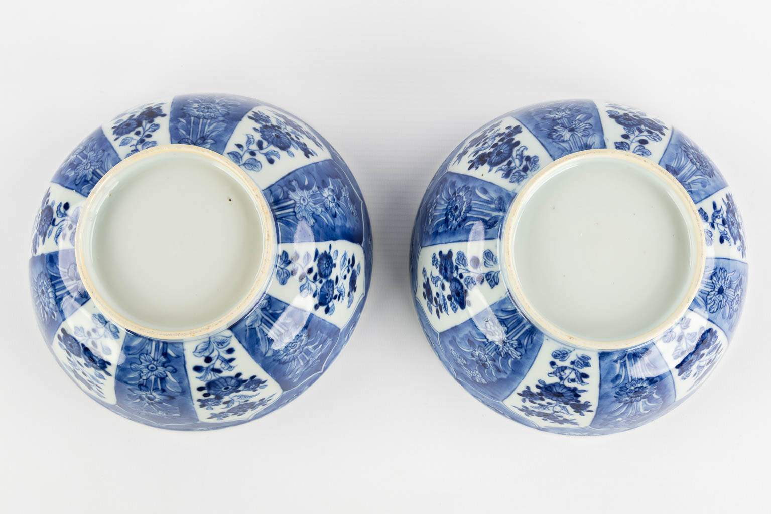 A pair of Chinese bowls, blue-white with a floral and pomegranate decor. 19th C. (H:8,5 x D:18 cm)