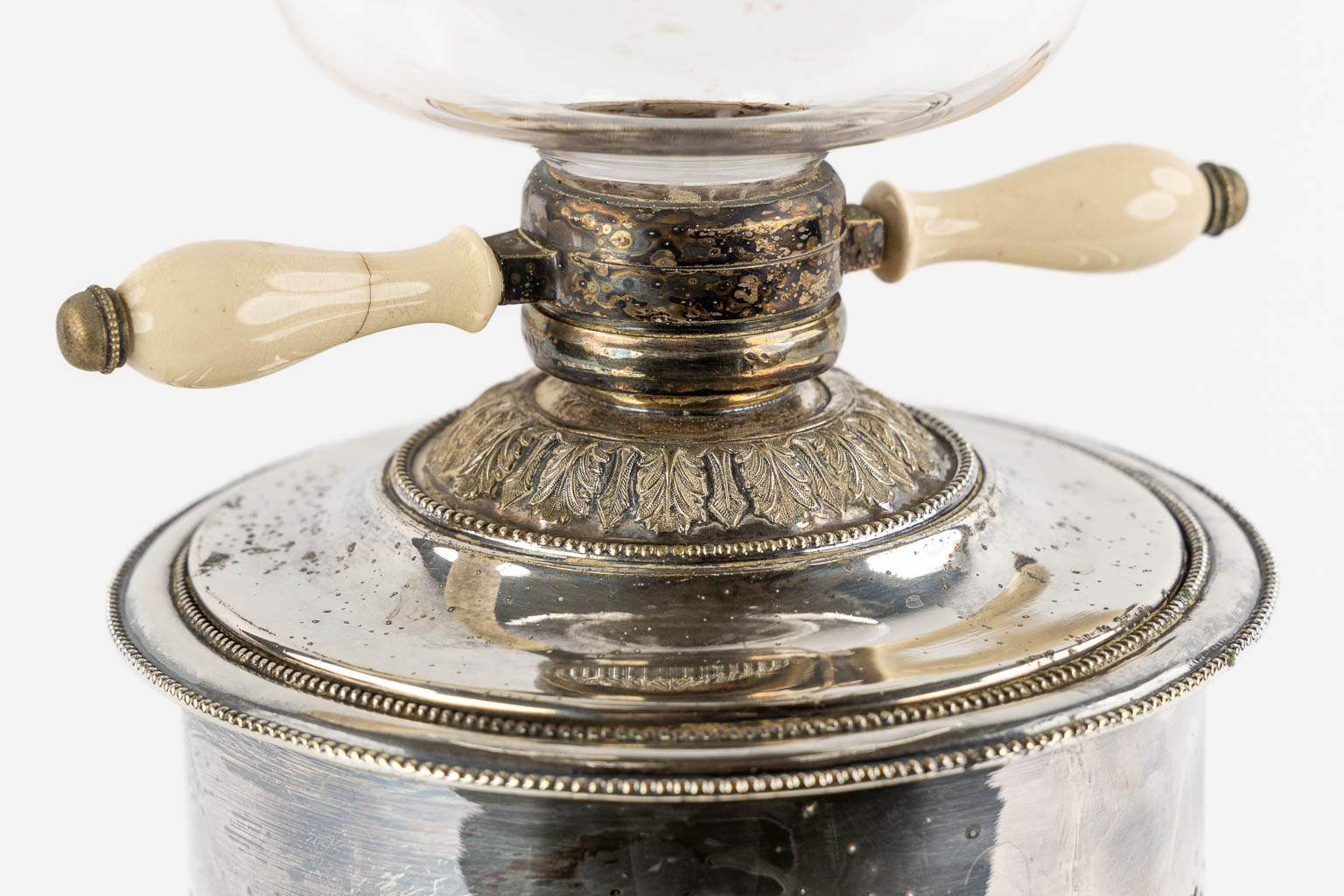 Een verzilverde samovar met glas, staande op leeuwen. (W:33 x H:51 cm)