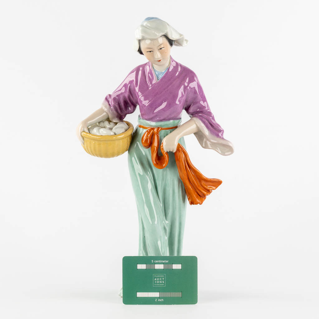 Een Chinees porseleinen figuur van een dame met mand. (L:11 x W:18 x H:32,5 cm)