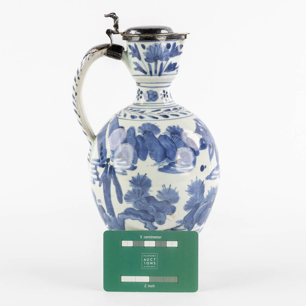 A Chinese pitcher, blue-white mounted with silver, Netherlands, 17th C. (L:12 x W:13 x H:25 cm)