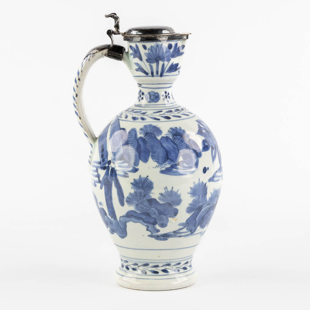 A Chinese pitcher, blue-white mounted with silver, Netherlands, 17th C. (L:12 x W:13 x H:25 cm)