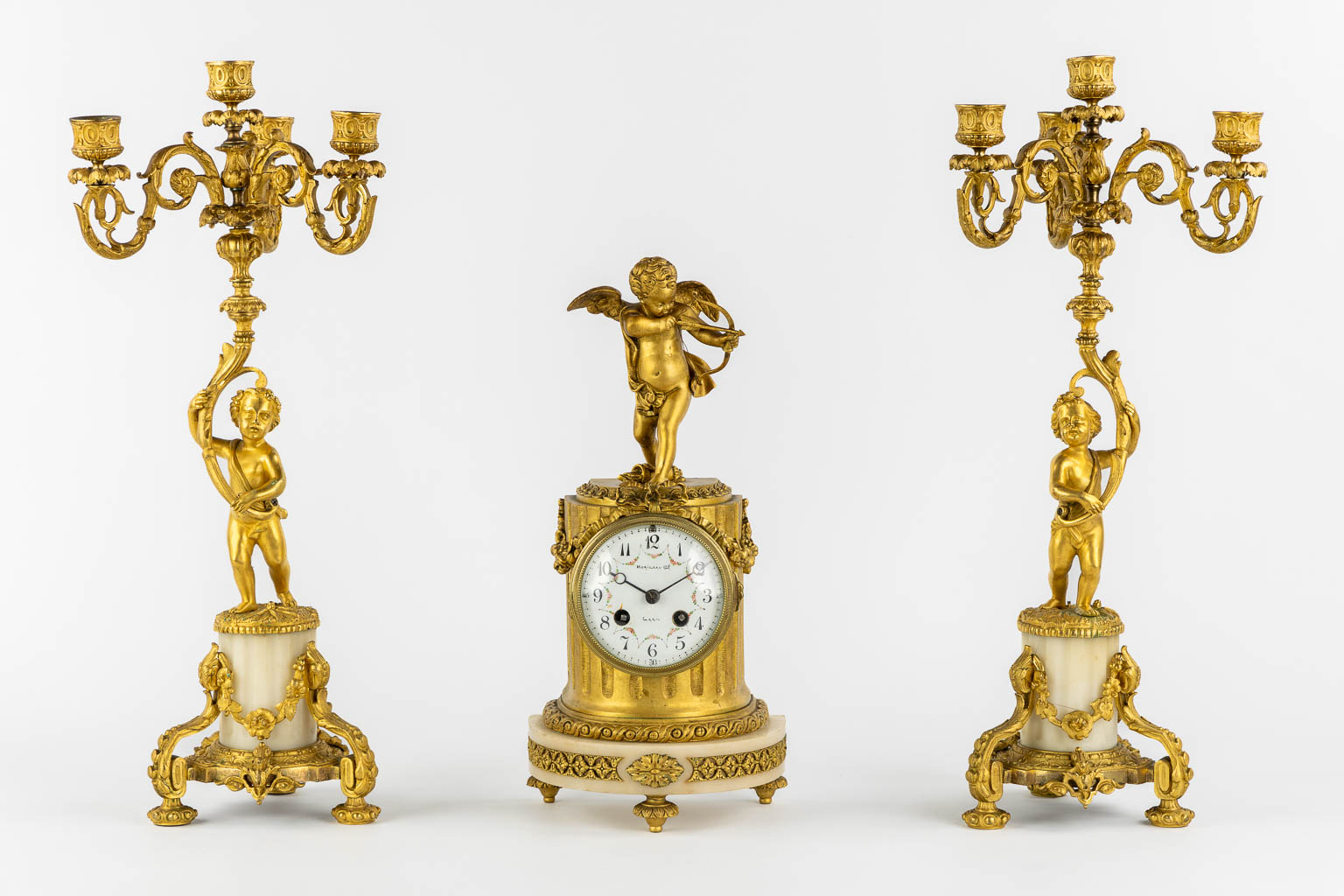 A three-piece mantle garniture clock, Cupid. Gilt bronze and Carrara marble. (L:13 x W:17 x H:37 cm)