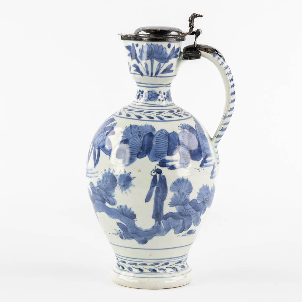 A Chinese pitcher, blue-white mounted with silver, Netherlands, 17th C. (L:12 x W:13 x H:25 cm)