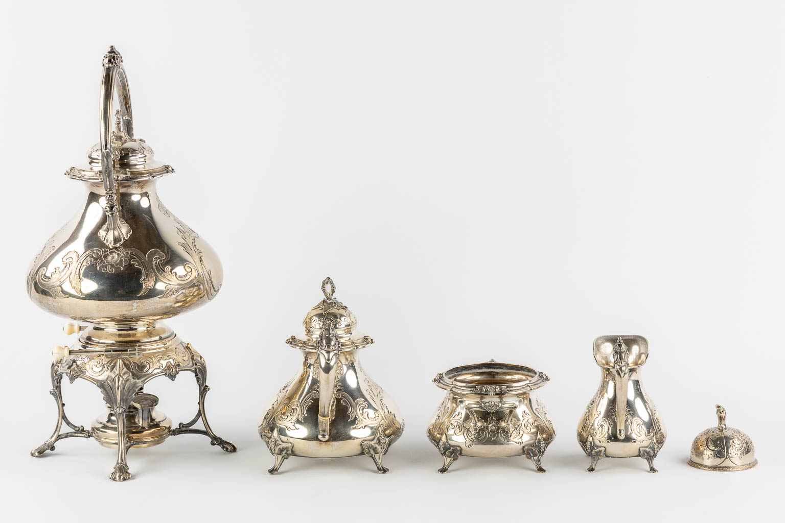 A silver-plated coffee and tea service with a samovar, sugar pot, milk jug and table bel. H&Co. (L:20 x W:26 x H:44 cm)