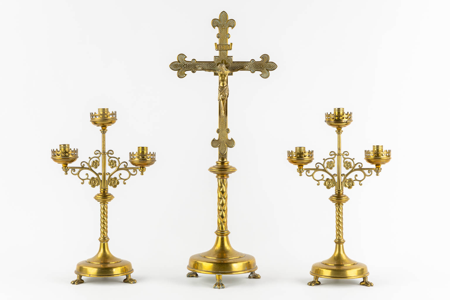 An altar crucifix with two matching candelabra, brass in a Gothic Revival style. (W:23 x H:58 cm)