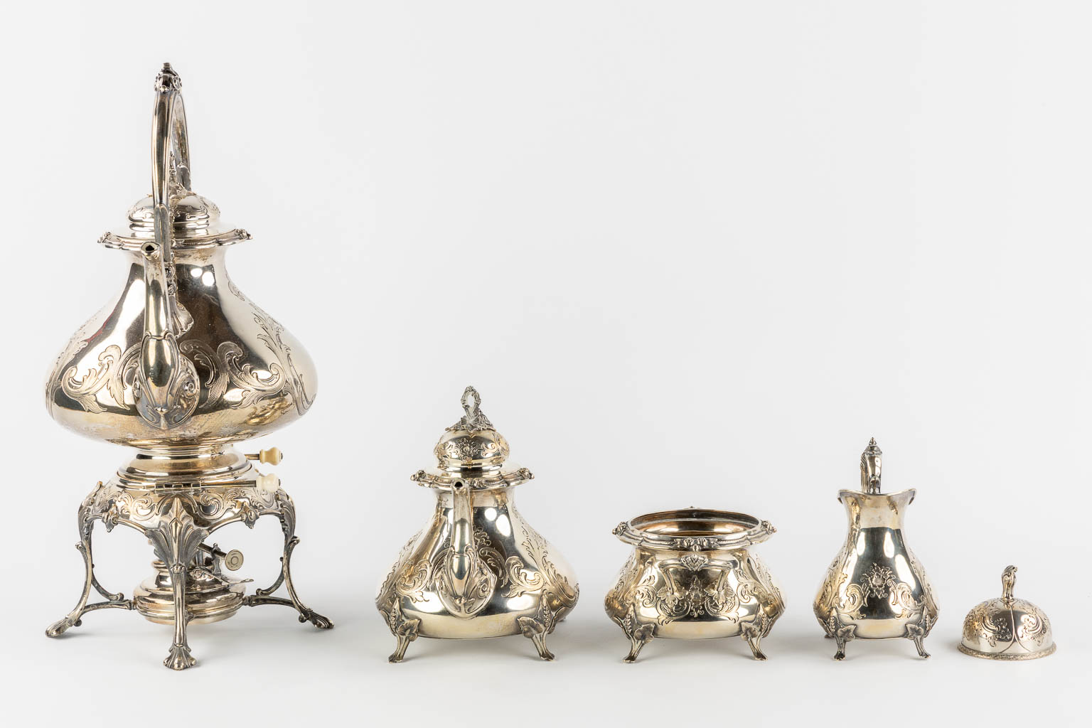 A silver-plated coffee and tea service with a samovar, sugar pot, milk jug and table bel. H&Co. (L:20 x W:26 x H:44 cm)