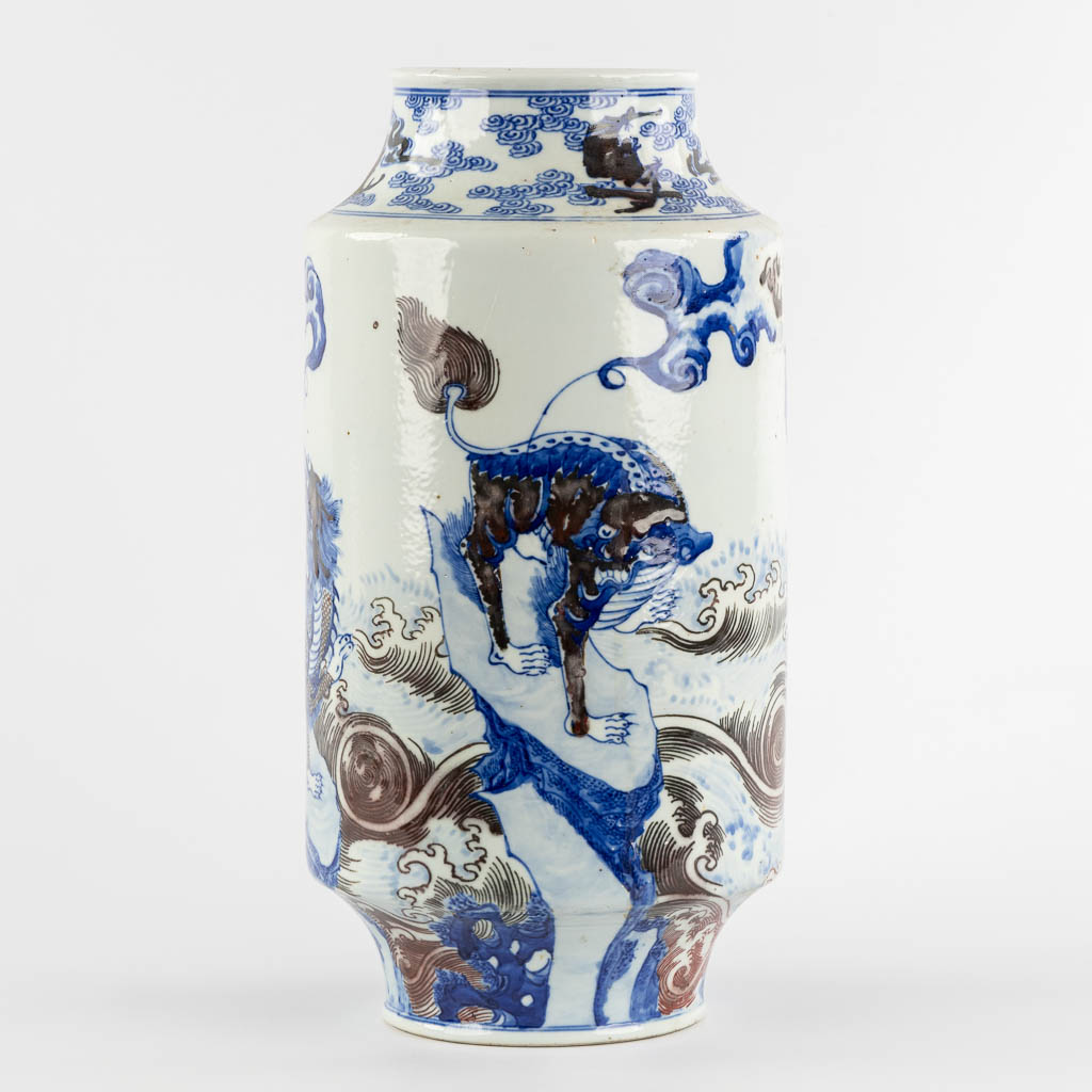 A Chinese Rouleau vase with a blue, black and white Foo Dog. Kangxi mark, 19th C. (H:39 x D:29 cm)