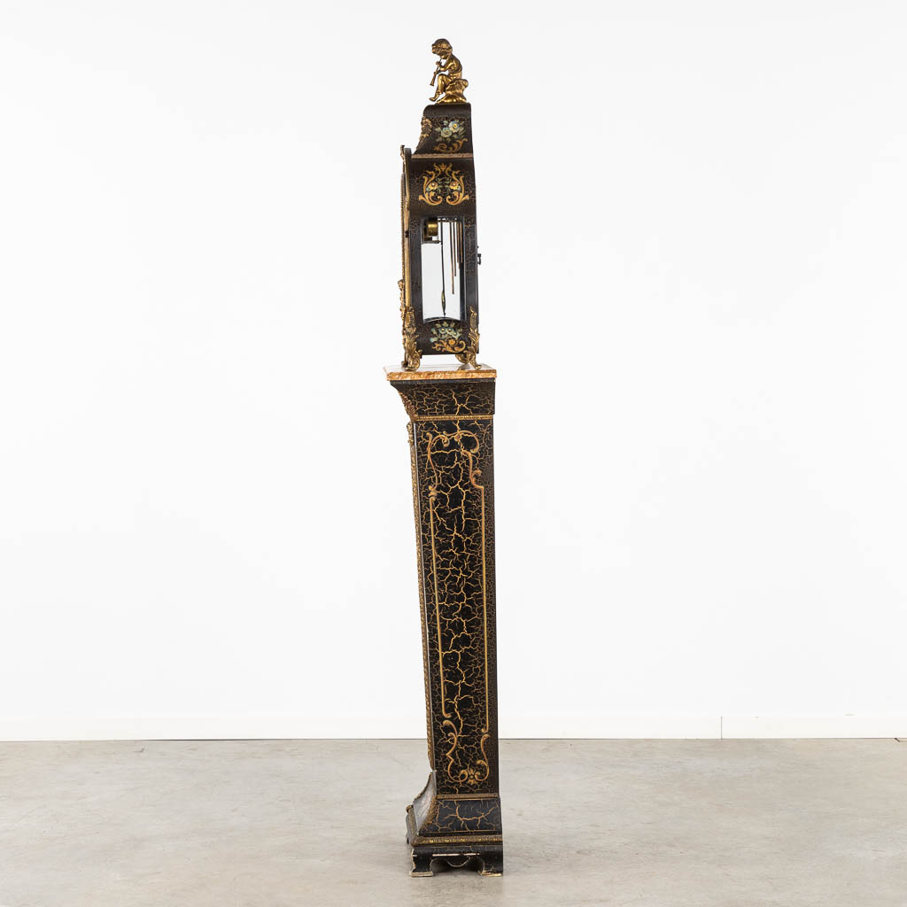 A cartel clock on a base, floral decor and mounted with putti. 20th C. (L:25 x W:44 x H:193 cm)