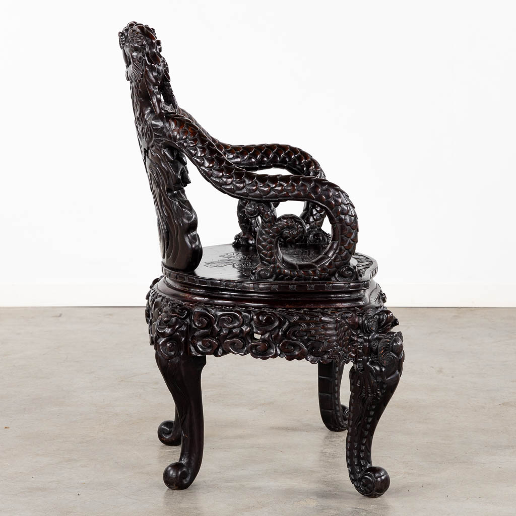 A Chinese sculptured hardwood armchair with a dragon decor. 