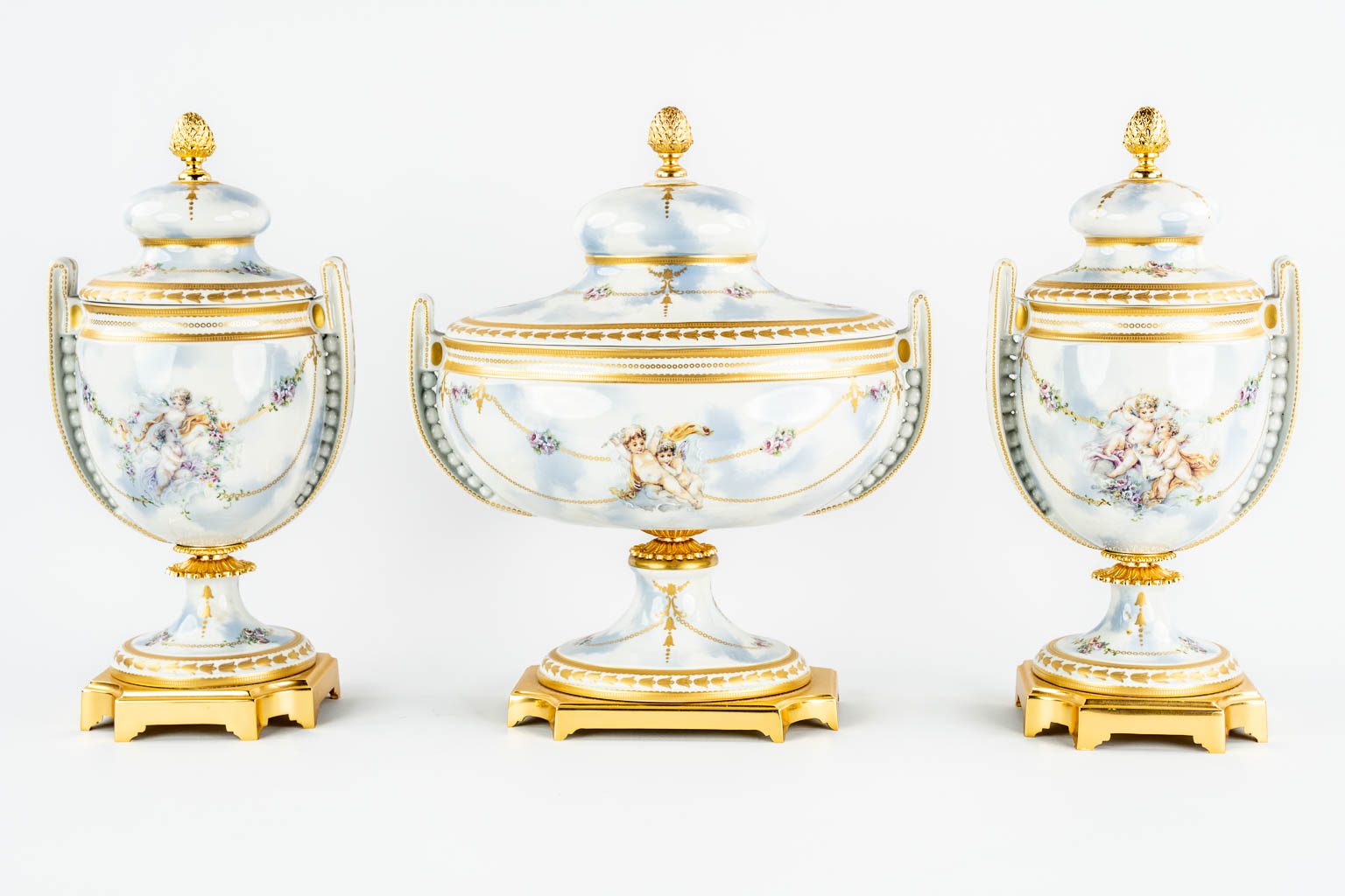 A three piece mantle garniture, porcelain vases with a lid, decorated with Angels. Italy, 20th C.