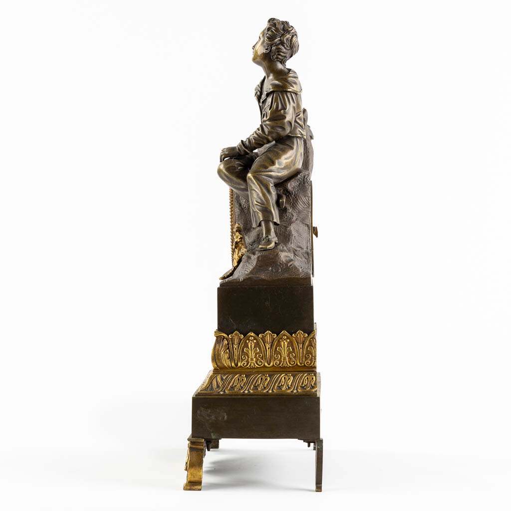 Een schouwklok, verguld en gepatineerd brons, Empire stijl. 19de eeuw. (L:13 x W:34 x H:46 cm)