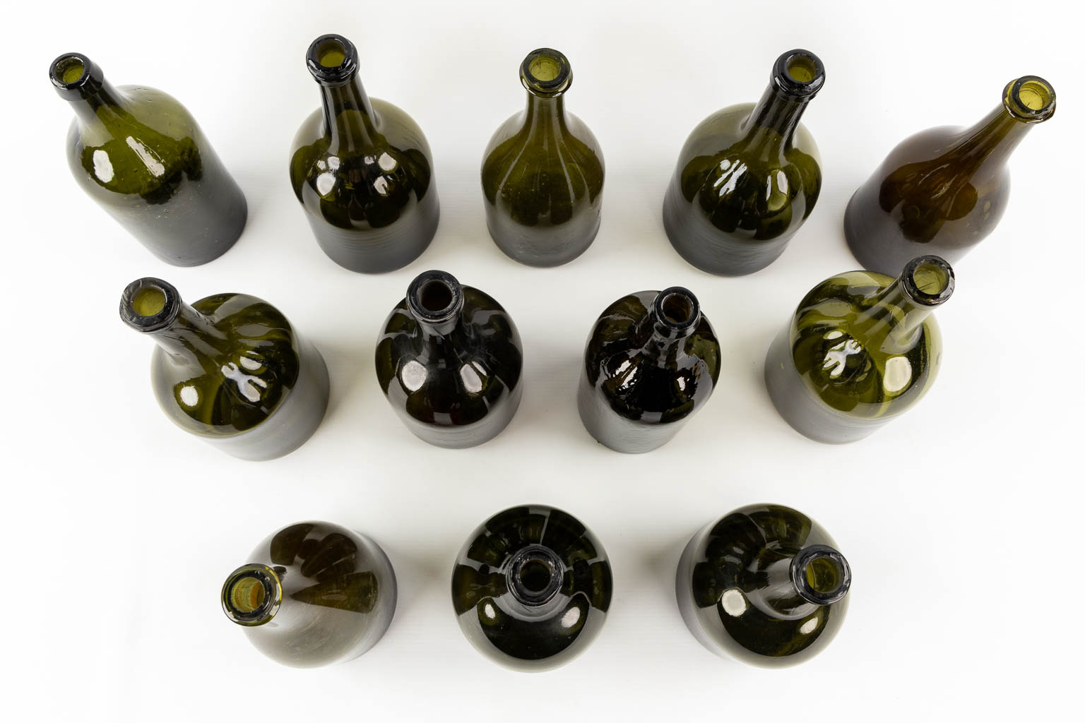 Twelve antique glass bottles, olive green glass. 18th and 19th C.