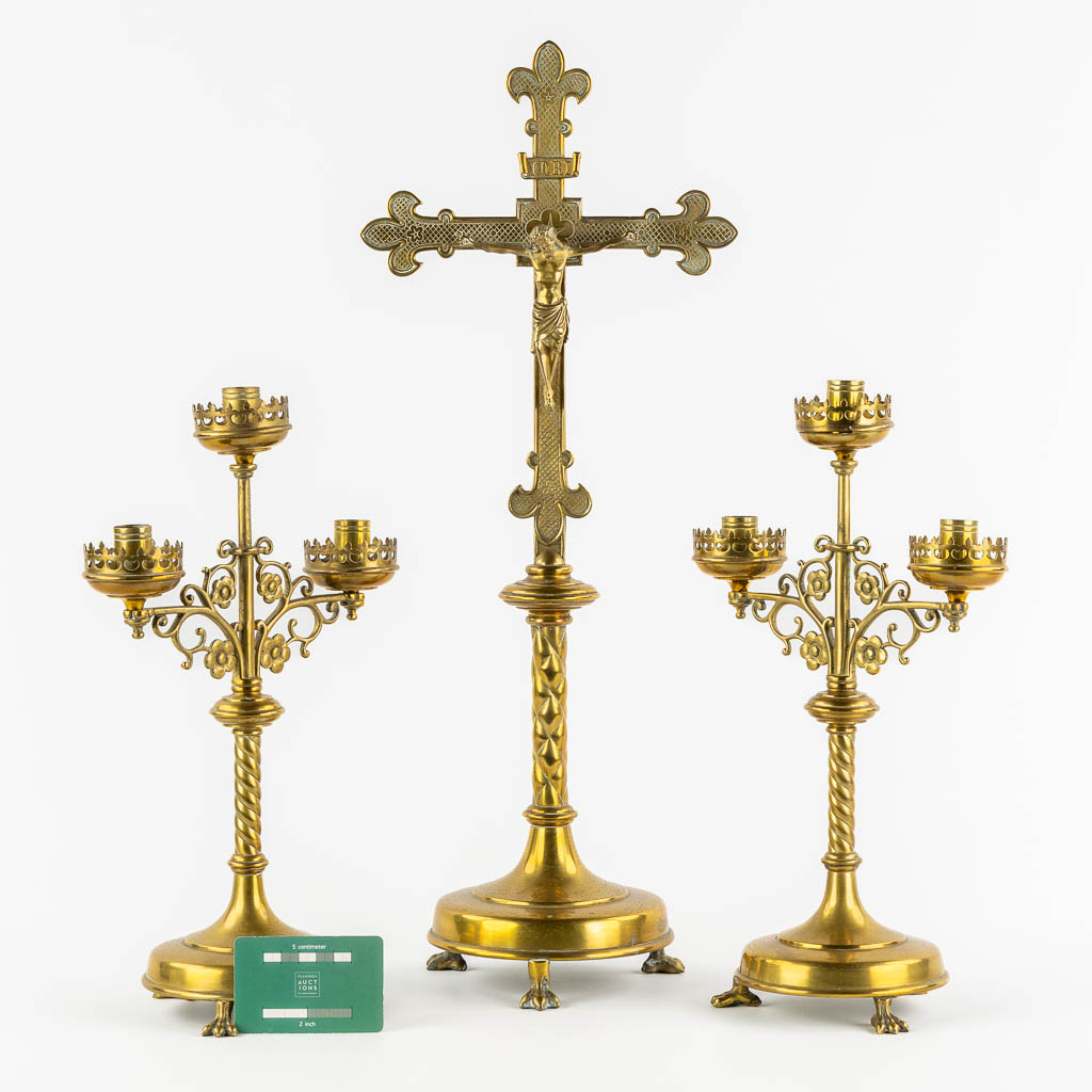 An altar crucifix with two matching candelabra, brass in a Gothic Revival style. (W:23 x H:58 cm)