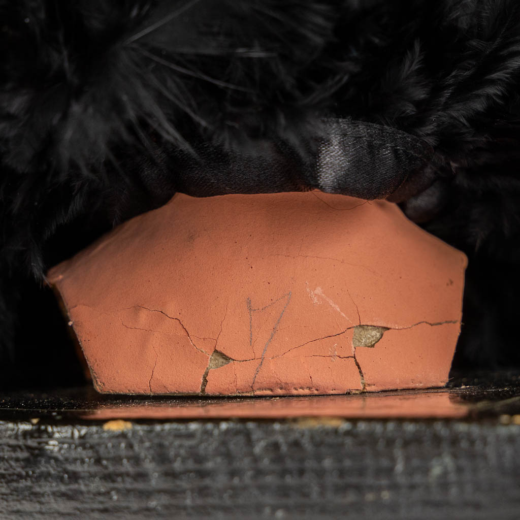 Een houten hoedenstaander met een papier maché poppenhoofd, glazen ogen. (H:27 cm)