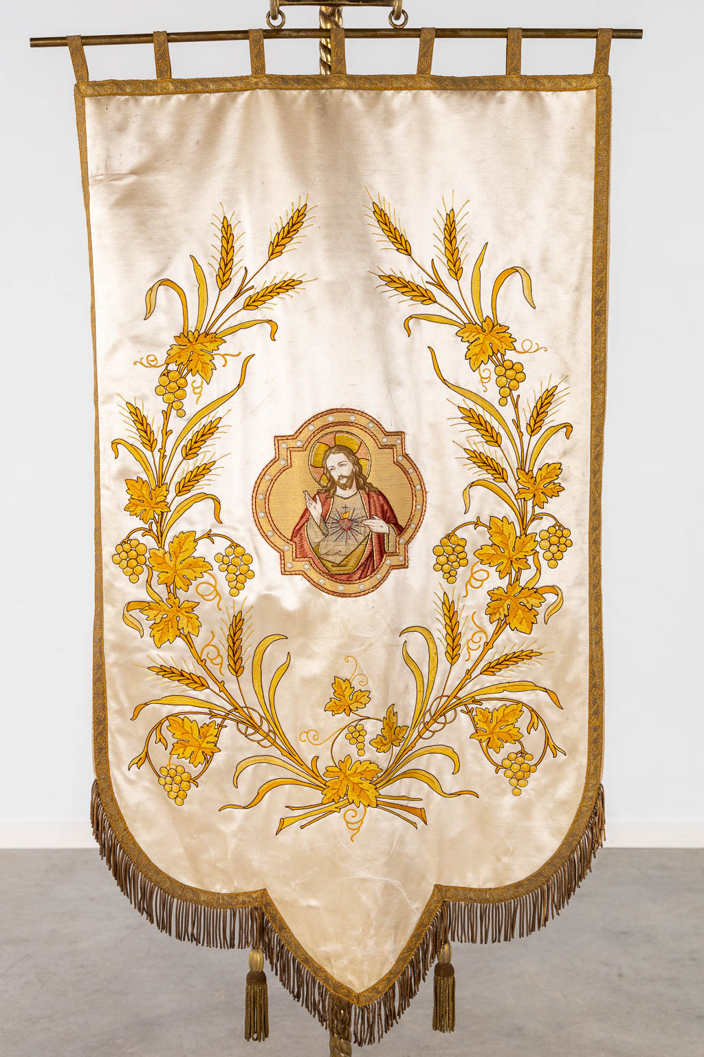 An embroidered banner on a brass holder, 