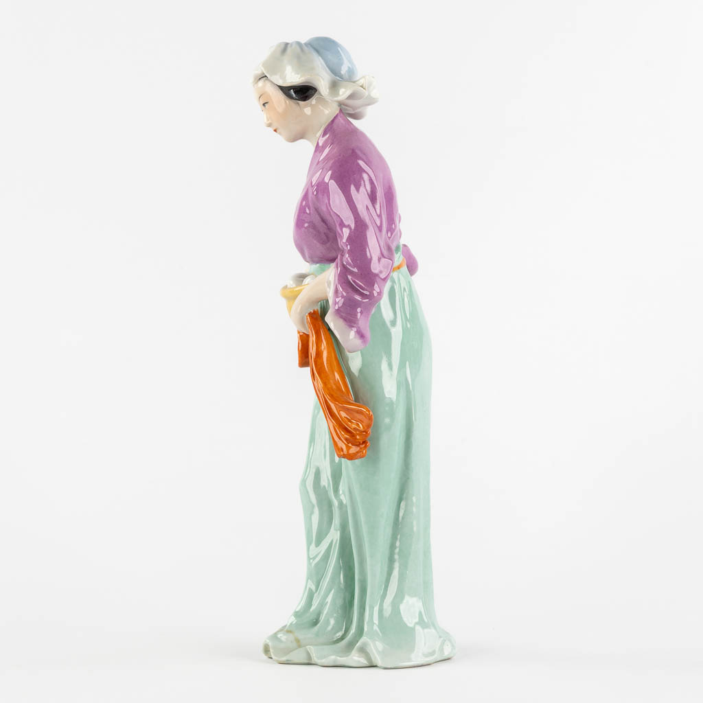 A Chinese porcelain figure of a lady with a basket. (L:11 x W:18 x H:32,5 cm)