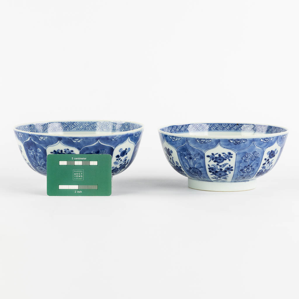 A pair of Chinese bowls, blue-white with a floral and pomegranate decor. 19th C. (H:8,5 x D:18 cm)